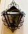 Decorative wrought-iron wall lantern featuring a textured glass panel and a metal crab accent inside the fixture.