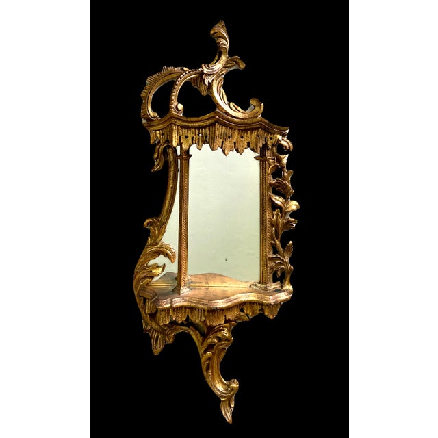 A superb example of an Italian gilt wood wall shelf with an integrated mirror, elegant asymmetrical scroll work influenced...