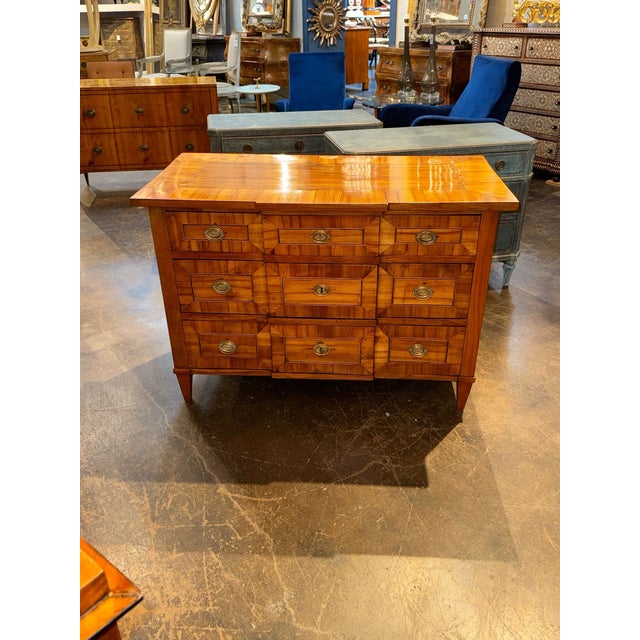 The product is an antique German Biedermeier inlaid walnut commode. This piece of furniture is a dresser or chest of...