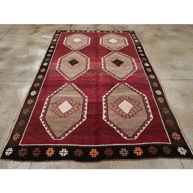 A wool pile with symmetric knots on a wool foundation. The slightly abrashed burgundy field features two pole medallions,...