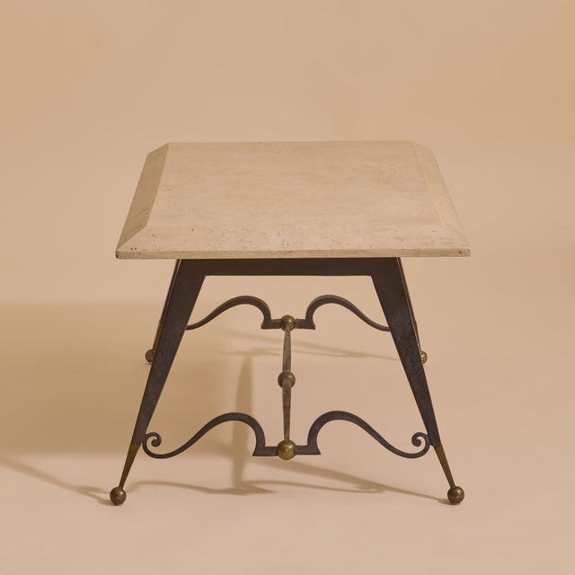 A study in restraint and quiet ornament, this French mid-century coffee table pairs a pale limestone top with a sculptural...