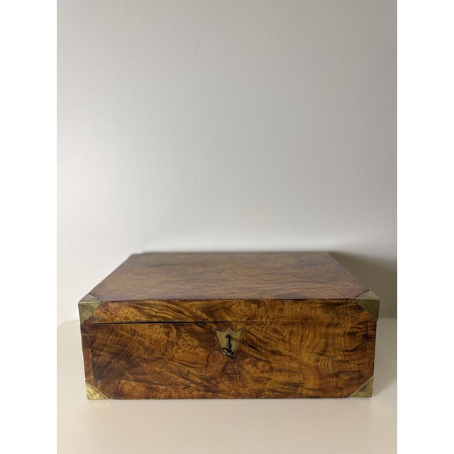 Walnut burl travel desk from the early 19th century. It features brass fittings and a central medallion on the top. This...