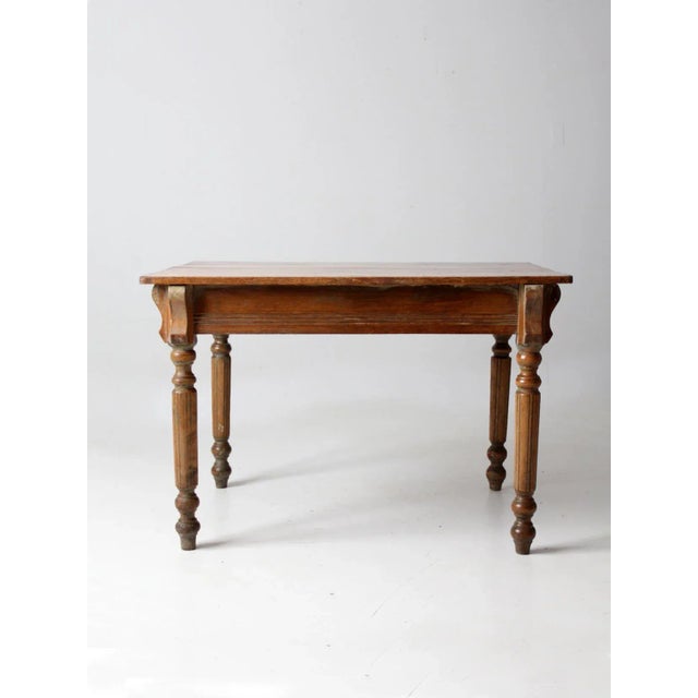 This is an antique wooden table. The farmhouse kitchen table features turned baluster style legs with an etched apron, and...