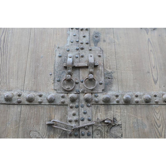 A dramatic antique compound door from Shanxi province, China, crafted from solid pine and reinforced with extensive hand-...