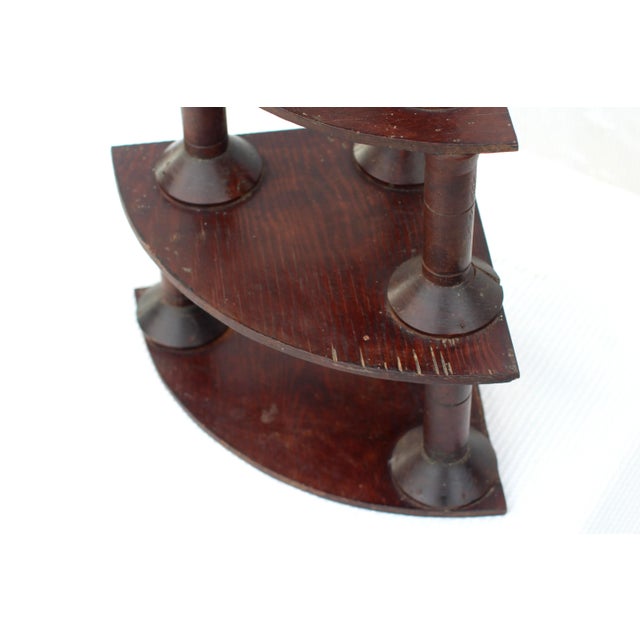 A triangular or pyramid corner shelf made of industrial spools. Antique dark stain finish with a hook to hang on the top....