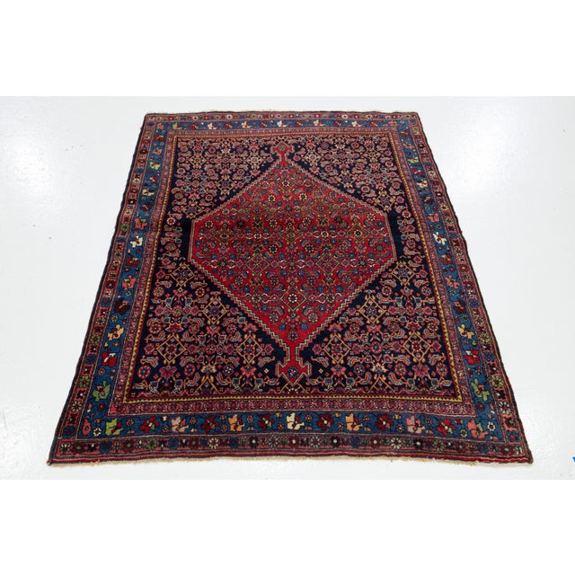 This Antique Bidjar Persian wool rug has a red and navy blue field with an all-over design in multicolor. This rug...