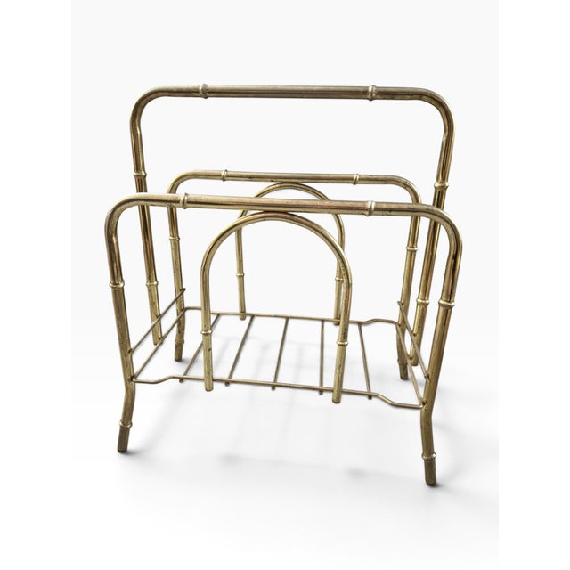 Elegant vintage Hollywood Regency magazine rack crafted in a warm gold-tone brass finish, featuring an unusually...