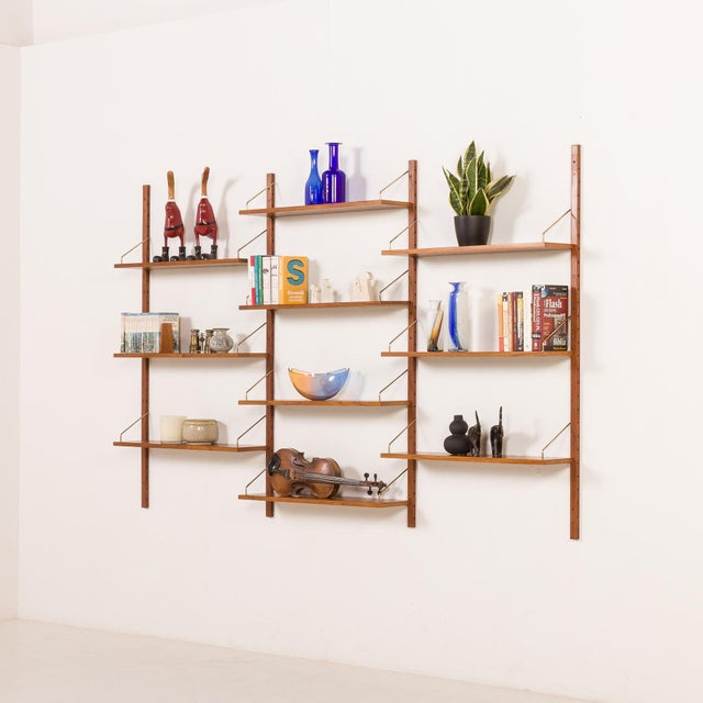 A classic composition of scandinavian teak shelves, hanging on solid wood rails and brass hangers. They were made in...
