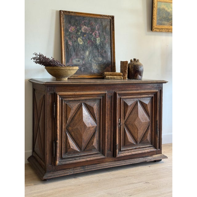 Heavy walnut with twin doors carved in deep diamond panels — raised lozenges set inside molded frames, the wood gone...
