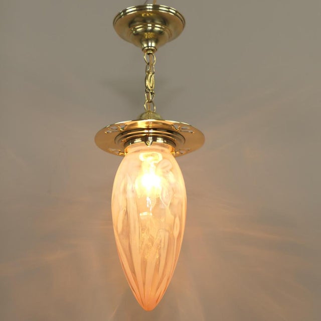 Rose-coloured Art Nouveau shade with floral pattern, 1910s The surface of the brass holder is polished. Total height with...