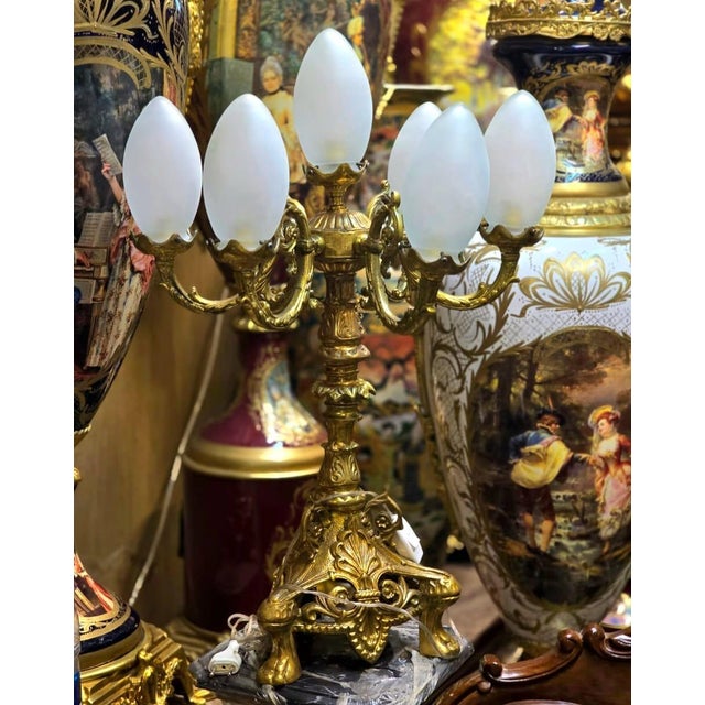 A stunning French Rococo style candelabra lamp featuring seven elegant lights supported by an ornate gilded bronze...
