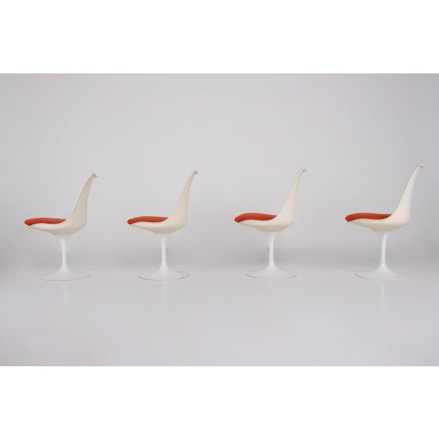 Set of four Tulip chairs by Eero Saarinen, in white lacquered cast aluminum, with fixed seats. Original cushions and...