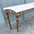 A refined vintage French Provincial console table featuring a beautifully veined white marble top and an elegant carved...