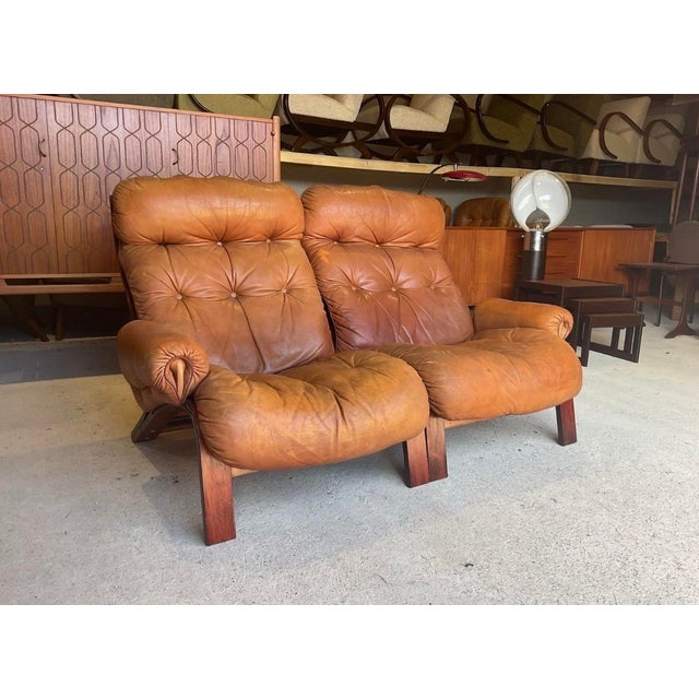 In good used condition with age related marks present. Stable and sound in construction! A rare tan leather sofa designed...