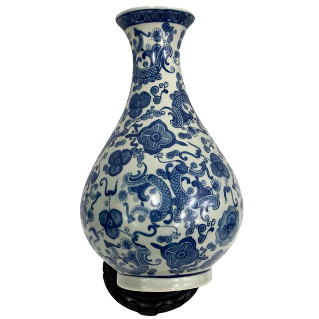 Vintage Blue and white porcelain vase features a beautiful floral pattern and sits on a lovely wooden base.