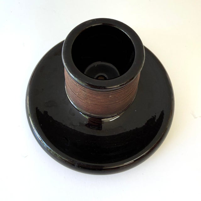 A classic antique English match striker in black glazed stoneware, featuring a ribbed cylindrical striking surface and...