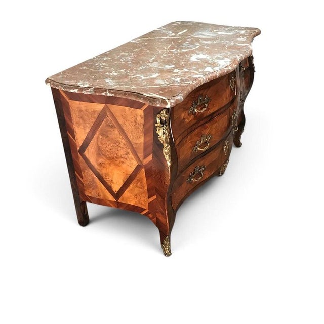 This elegant french louis xv style marquetry commode features a beautifully curved bombe form, richly figured wood...