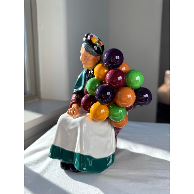 “The Old Balloon Seller” (H.N. 1315), introduced by Royal Doulton in 1935, is a finely modeled bone china figurine from...