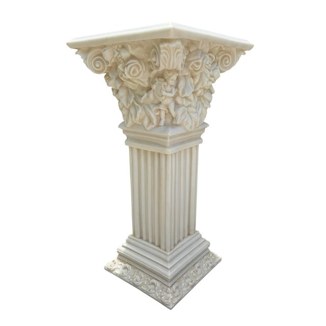 A vintage faux alabaster resin pedestal featuring a richly detailed Corinthian capital adorned with sculpted cherubs,...