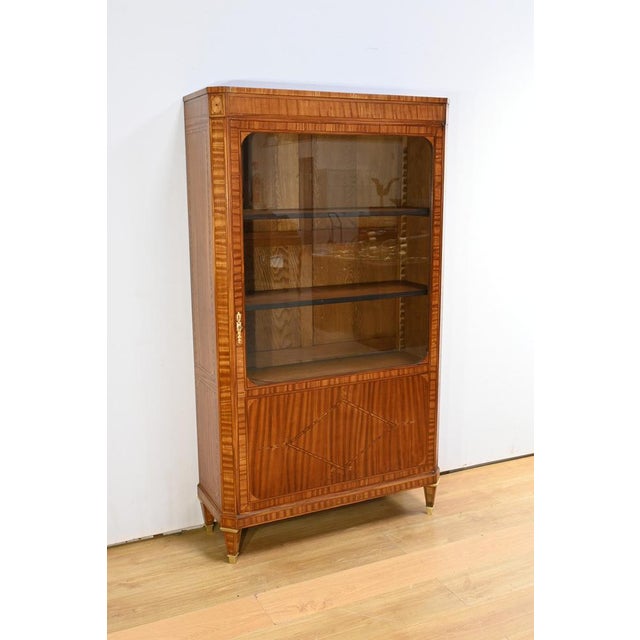 This flamed mahogany veneer bookcase is an exceptional piece that combines elegance and functionality. It opens with a...