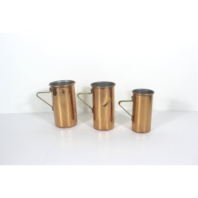 Vintage set of three copper measuring cups with brass handles. Marked on the bottoms: 1 CUP 3/4 CUP 1/2 CUP CONDITION:...