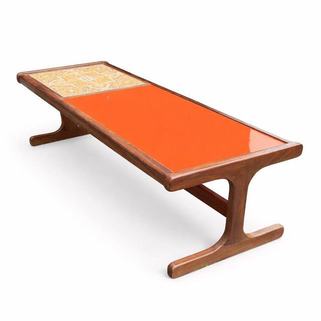 A striking mid-century G Plan coffee table featuring a bold orange acrylic glass inset and decorative tiled panel, set...
