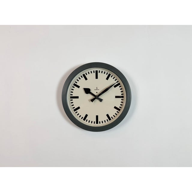 This wall clock was produced by Siemens in Germany during the 1950s. It features a grey iron frame, a metal dial and a...