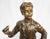A bronze figure of a boy. French, mid to early 20th century. Mid brown patination. Shown standing wearing braces and...