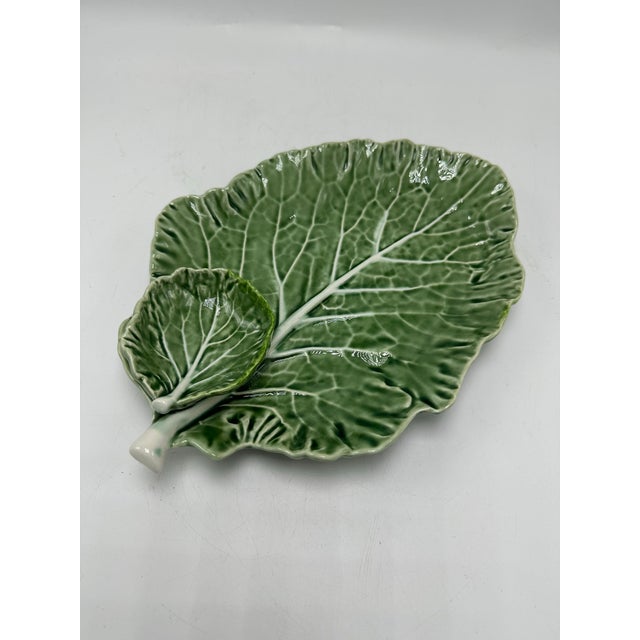 This is a beautiful ceramic serving dish designed in the shape of a cabbage or lettuce leaf. The textured surface,...