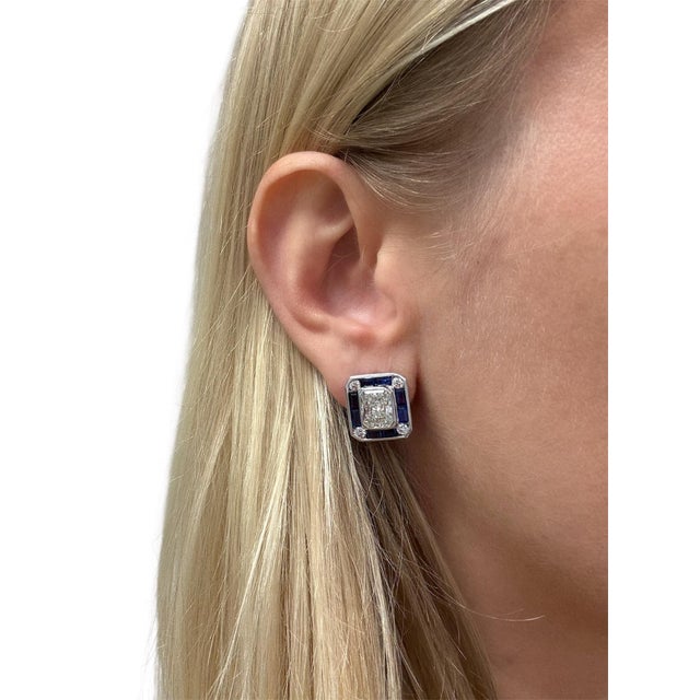 These beautiful earrings contain two radiant cut diamonds weighing 2.19 and 2.15 carats, surrounded by rectangular step...