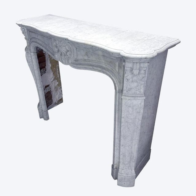 A carved Carrara Marble antique 19th century Louis XV style "Tres Coquilles" fireplace. The Cantered console jambs with...