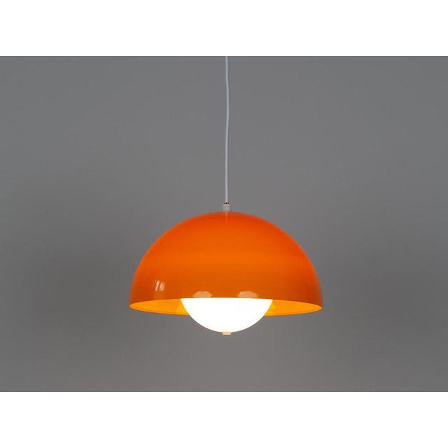 A pair of unique space-age lamps from the 1970s in a vibrant orange. The lamps feature a timeless, geometric shape based...