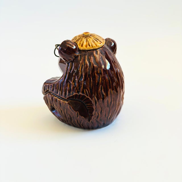 A vintage ceramic ashtray in the shape of a bear wearing wire glasses. Features a large opening with a cigarette rest and...