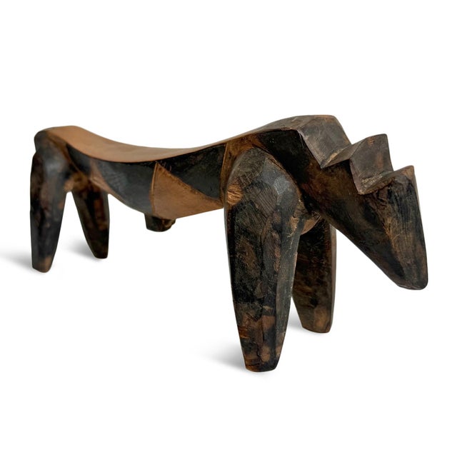 This carved wooden African headrest from the Congo features an elongated, gently curved top supported by four sturdy legs,...
