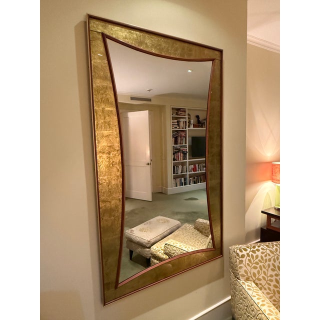 A dramatic Hollywood Regency-style wall mirror, measuring an impressive 65" x 39". The frame is richly textured gold leaf...