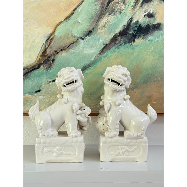 A lovely pair of vintage white ceramic Foo Dogs (Chinese Guardian Lions). Produced in the mid 20th century. Featuring a...