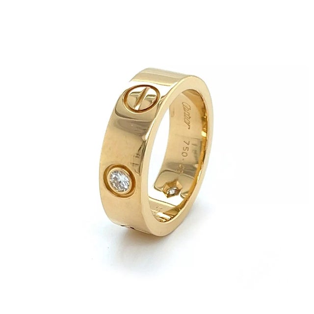 This authentic Cartier Love ring is crafted from 18k yellow gold with a fine polished finish with three round cut...