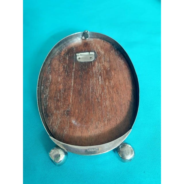 Charming antique oval sterling silver picture frame featuring an elegant bamboo-inspired border and two spherical feet....