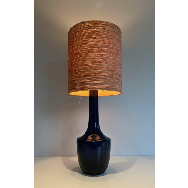 This very beautiful table lamp is made of blown blue glass with a raffia lampshade. This is a French or Italian work....