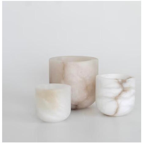 The Luce Tealight Holder by Michael Verheyden highlights the soft, translucent beauty of alabaster, casting a warm,...