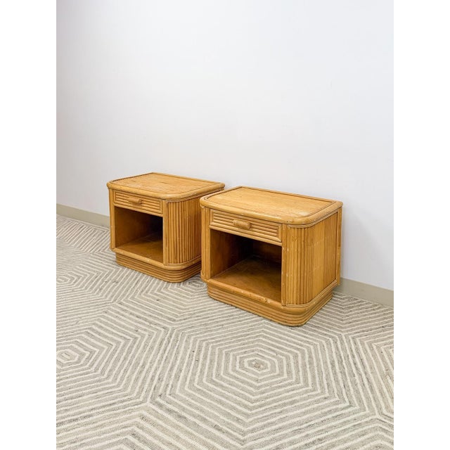 This charming pair of vintage blonde pencil reed rattan nightstands are a warm and highly covetable coastal and Hollywood...