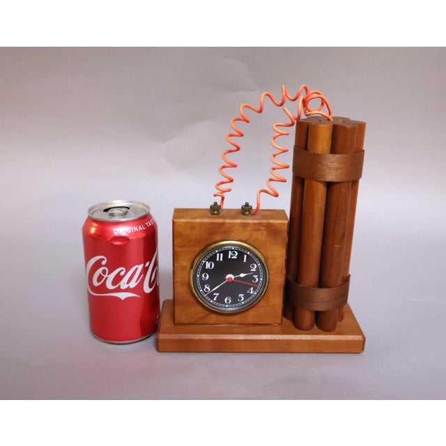 A whimsical vintage folk art desk clock designed in the form of a bundle of dynamite connected to a timing mechanism by a...