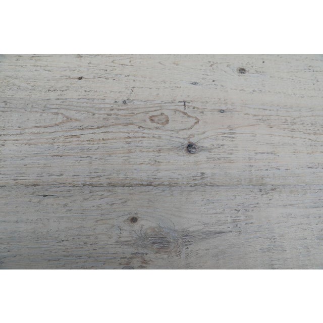 A striking round dining table combining a reclaimed pinewood top with a sculptural iron cone pedestal base. The thick wood...