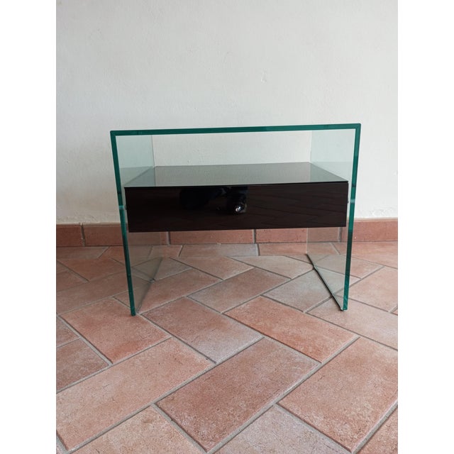 The "Secret" bedside table features a minimalist design and a bridge-shaped structure made entirely of glass. The glass...