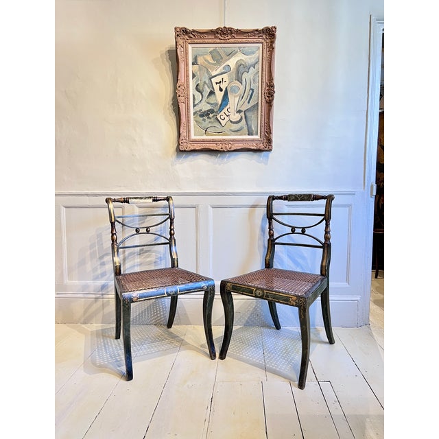 A decorative pair of painted side chairs in the regency taste, likely early 19th century english. The dark green ground...