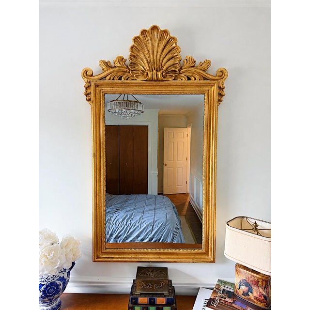 A vintage Italian gilt-wood wall mirror by Ethan Allen, distinguished by an oversized scallop/shell crest and scrolling...