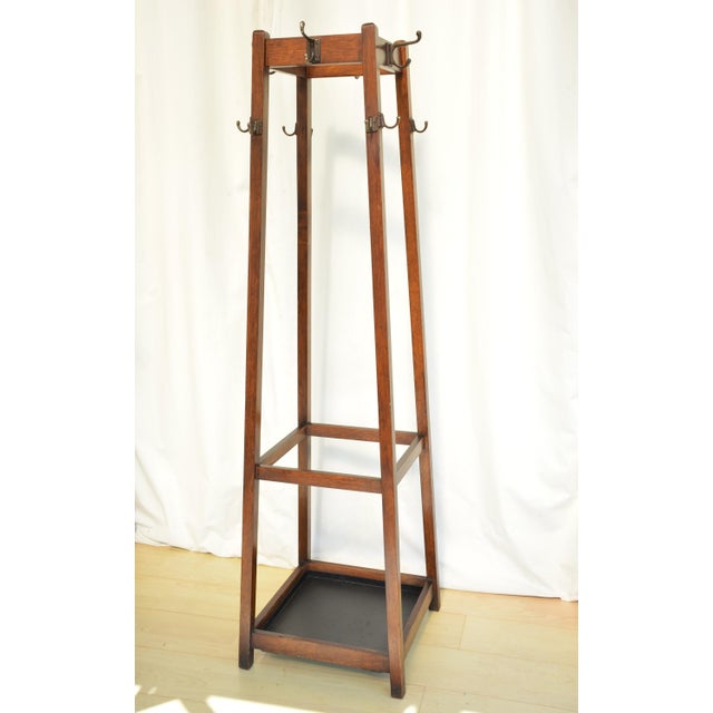 English antique Arts and Crafts coat stand, having four double coat and hat hook above eight single hooks on four square...
