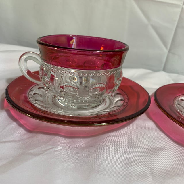 These vintage items are King's Crown pattern cups and saucers, featuring a clear thumbprint pressed glass design accented...