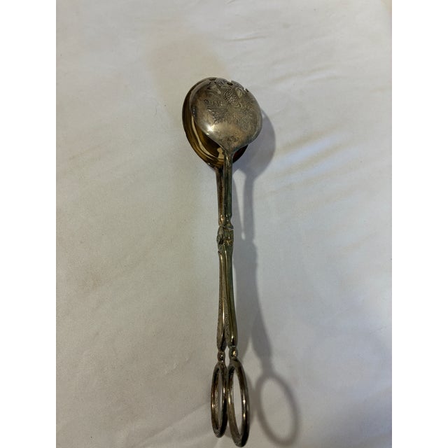 Elegant vintage silverplate serving tongs made in Italy featuring a distinctive scissor-style mechanism and decorative...
