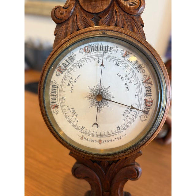 antique barometer with wood carving includes a dual-scale thermometer measuring temperature in both Fahrenheit and...